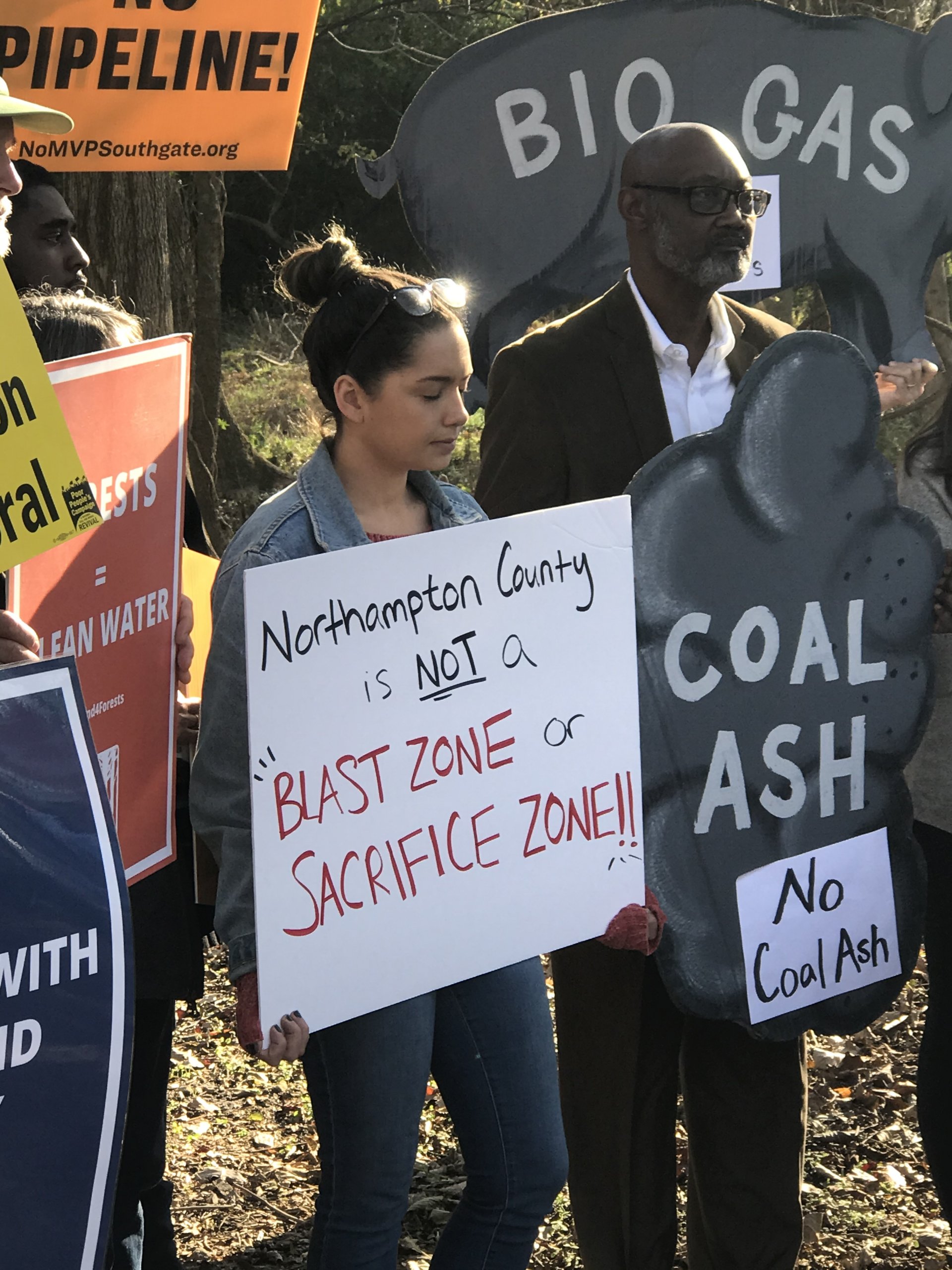 Rachel Velez of Clean Water for North Carolina holds a sign that reads "Northampton County is not a Blast Zone or Sacrifice Zone" in front of other sign-holders