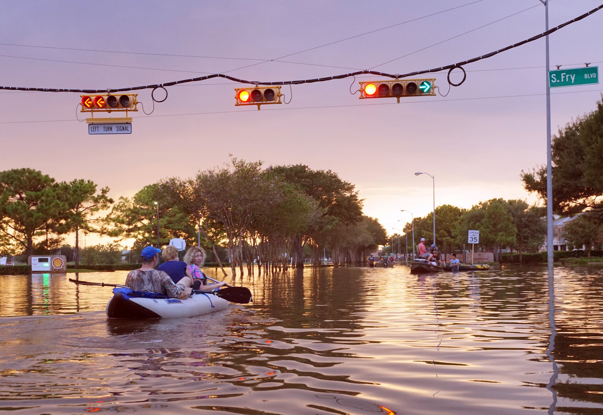 people drive a boat down a flooded street